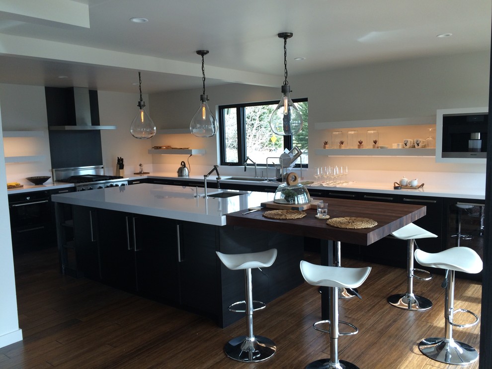 Photo of a large modern u-shaped open plan kitchen in Salt Lake City with stainless steel appliances, with island, an undermount sink, flat-panel cabinets, black cabinets, quartz benchtops and medium hardwood floors.