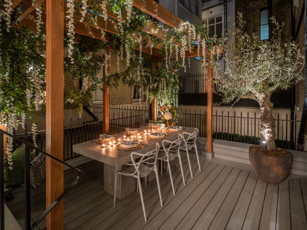 This is an example of a mid-sized traditional courtyard and ground level deck in London with no cover and wood railing.