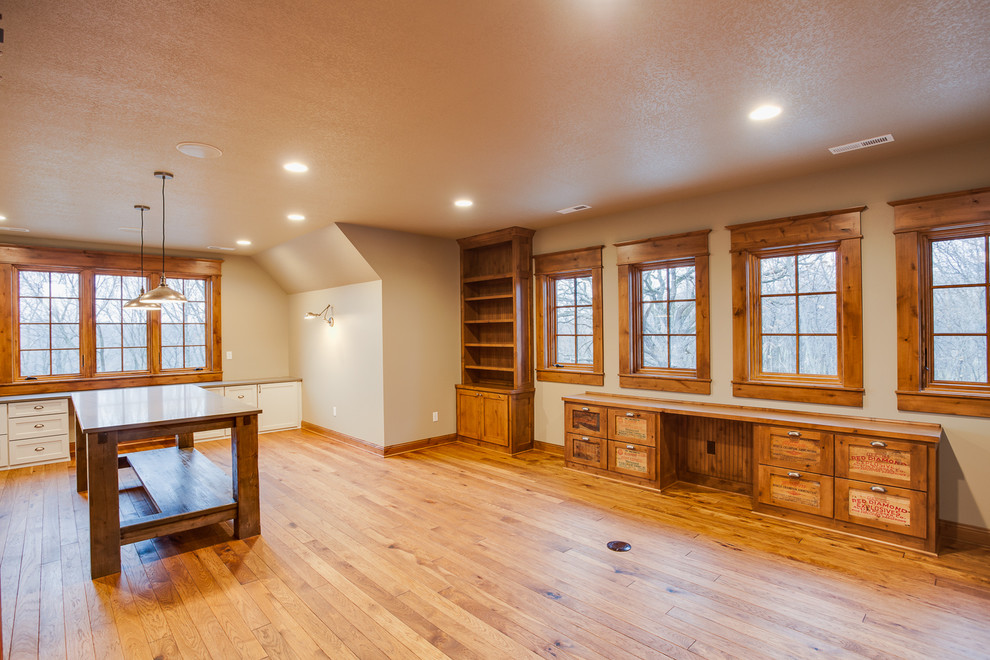 Large mountain style built-in desk medium tone wood floor study room photo with beige walls