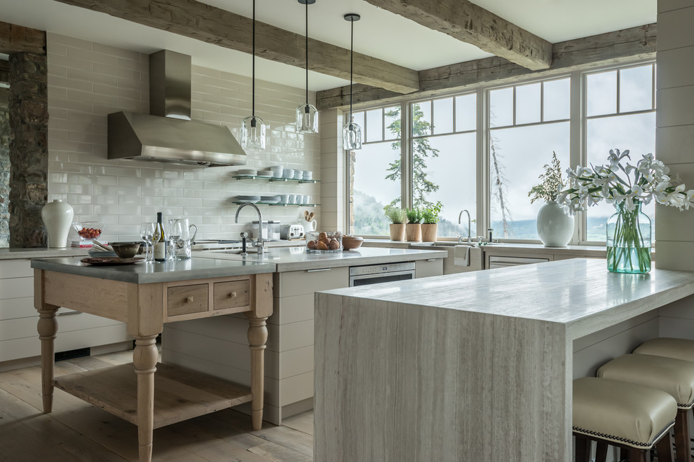 Inspiration for a country u-shaped kitchen in Other with a farmhouse sink, flat-panel cabinets, beige cabinets, white splashback, stainless steel appliances, light hardwood floors, with island, beige floor and grey benchtop.