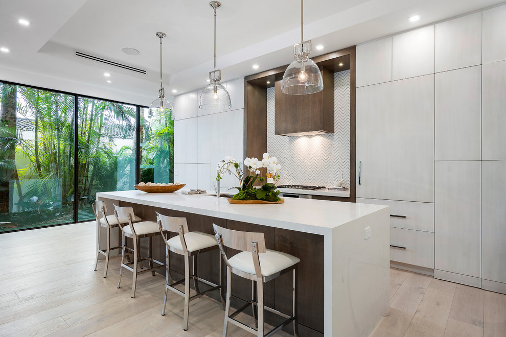 Design ideas for a contemporary kitchen in Miami with flat-panel cabinets, white cabinets, panelled appliances, light hardwood floors, with island, beige floor and white benchtop.