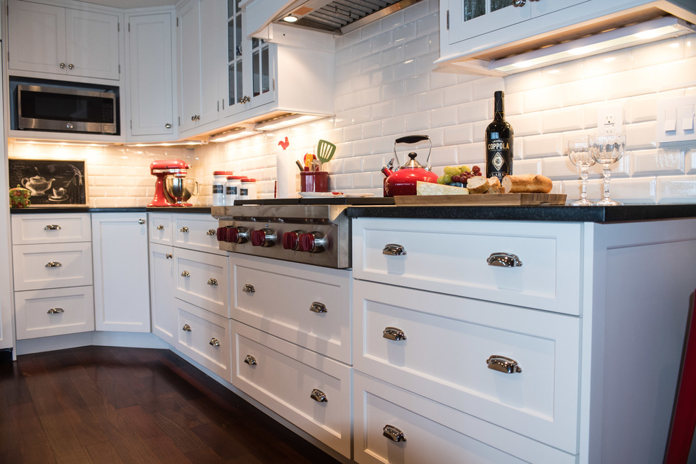 Design ideas for a country kitchen in Baltimore with a farmhouse sink, shaker cabinets, white cabinets, white splashback, subway tile splashback, stainless steel appliances, dark hardwood floors and multiple islands.