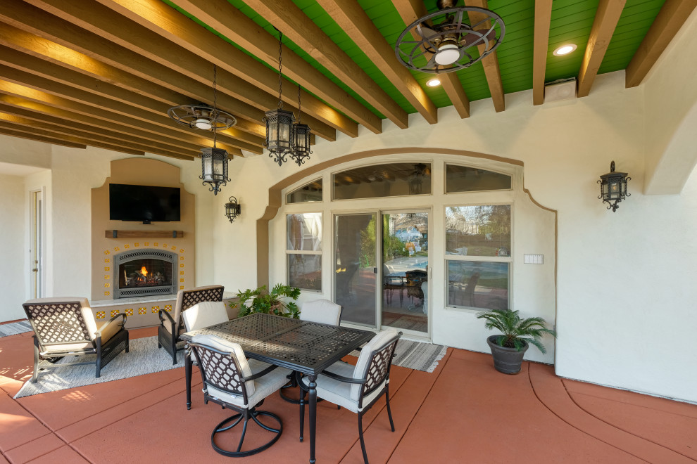 Photo of a large mediterranean back patio in Sacramento with a fireplace, concrete slabs and a roof extension.