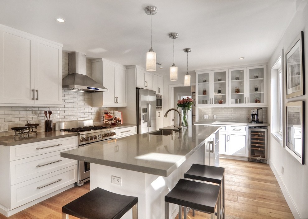 Inspiration for a large contemporary l-shaped kitchen in Orange County with a farmhouse sink, shaker cabinets, white cabinets, white splashback, subway tile splashback, stainless steel appliances and with island.