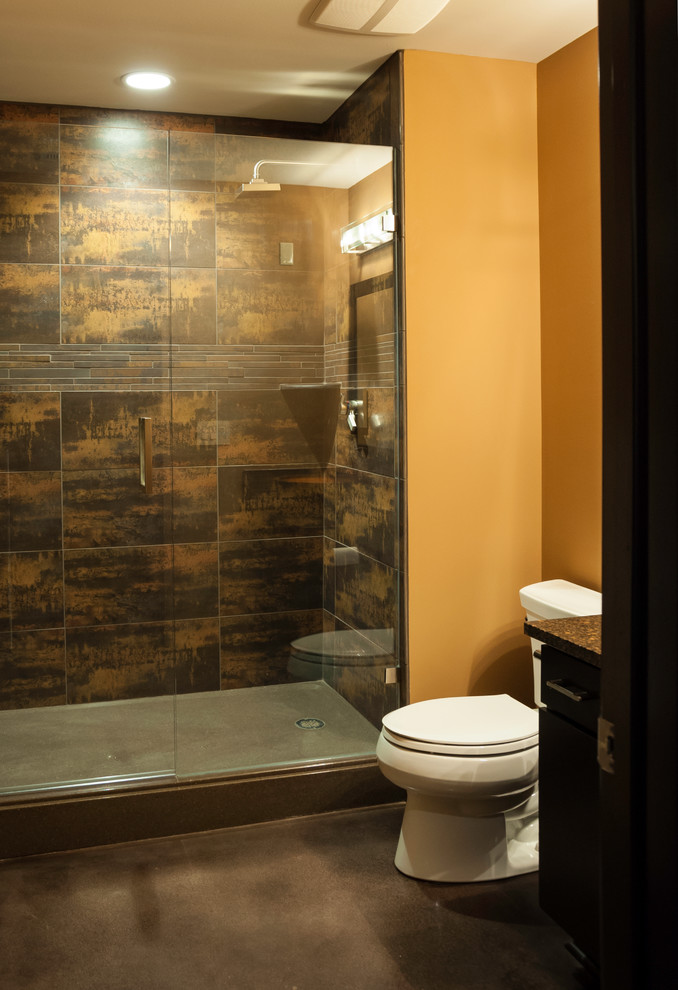 Photo of a small modern 3/4 bathroom in Wichita with a vessel sink, flat-panel cabinets, dark wood cabinets, granite benchtops, an alcove shower, brown tile, porcelain tile, orange walls, concrete floors, grey floor and a hinged shower door.