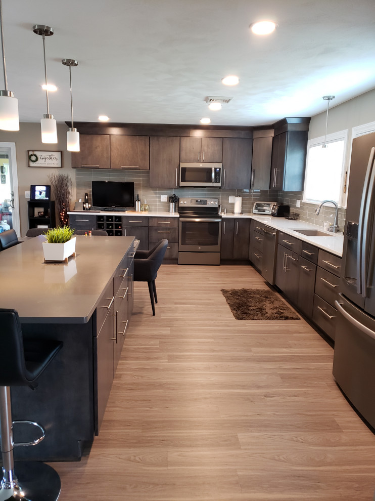 Design ideas for a large contemporary l-shaped eat-in kitchen in Chicago with an undermount sink, flat-panel cabinets, grey cabinets, quartz benchtops, grey splashback, glass tile splashback, stainless steel appliances, vinyl floors, grey floor, white benchtop and with island.