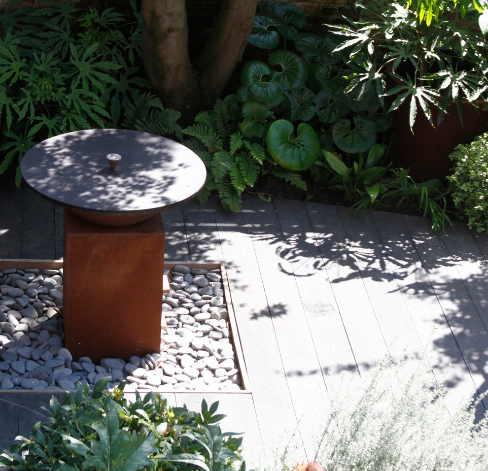 This is an example of a small modern backyard partial sun garden for summer in London with natural stone pavers.