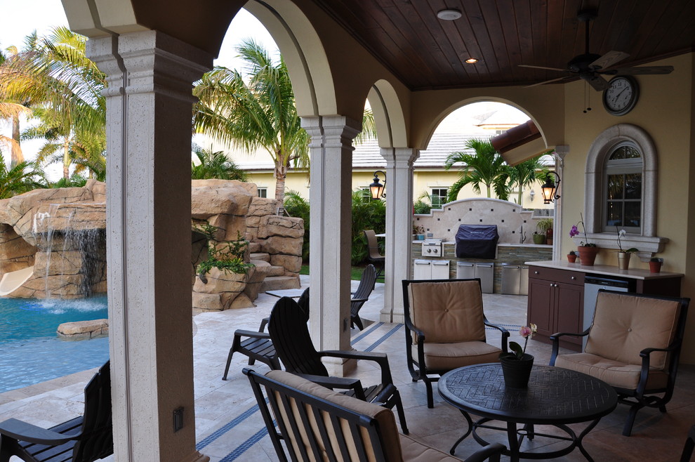 Inspiration for a mediterranean backyard patio in Miami with natural stone pavers and a roof extension.