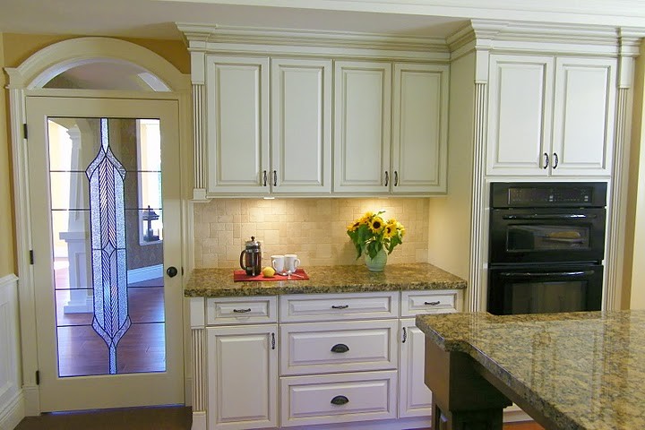 Photo of a traditional u-shaped eat-in kitchen in Vancouver with an undermount sink, raised-panel cabinets, white cabinets, granite benchtops, beige splashback and panelled appliances.