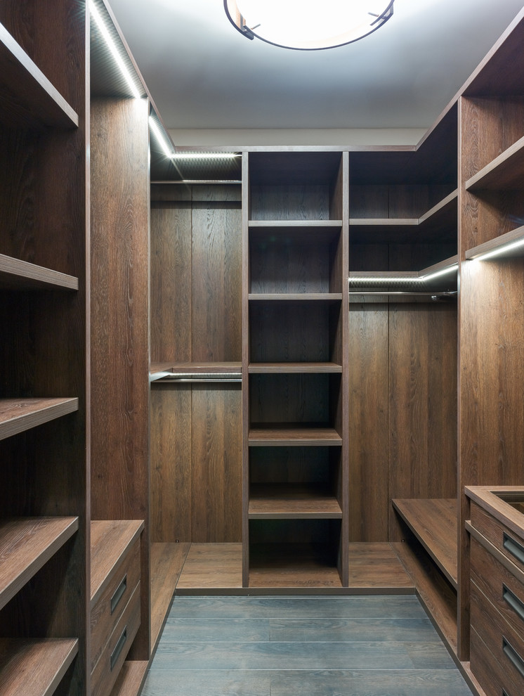 Contemporary gender-neutral walk-in wardrobe in Moscow with open cabinets, dark wood cabinets and dark hardwood floors.