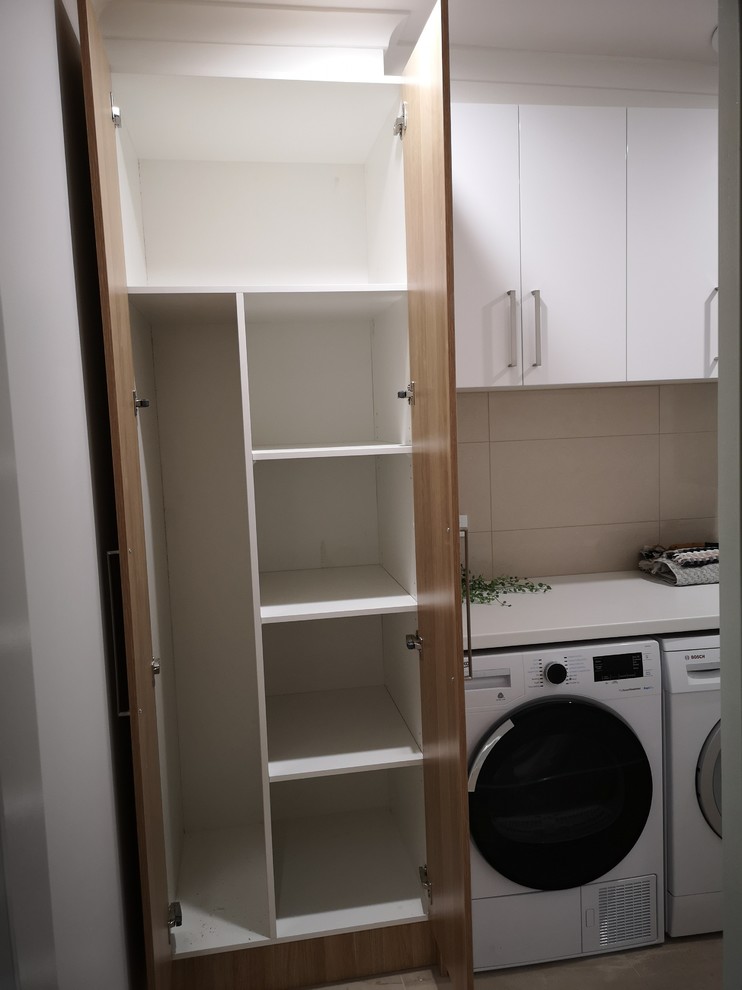 This is an example of a small modern single-wall dedicated laundry room in Melbourne with a drop-in sink, recessed-panel cabinets, light wood cabinets, laminate benchtops, beige walls, porcelain floors, a side-by-side washer and dryer, beige floor and white benchtop.