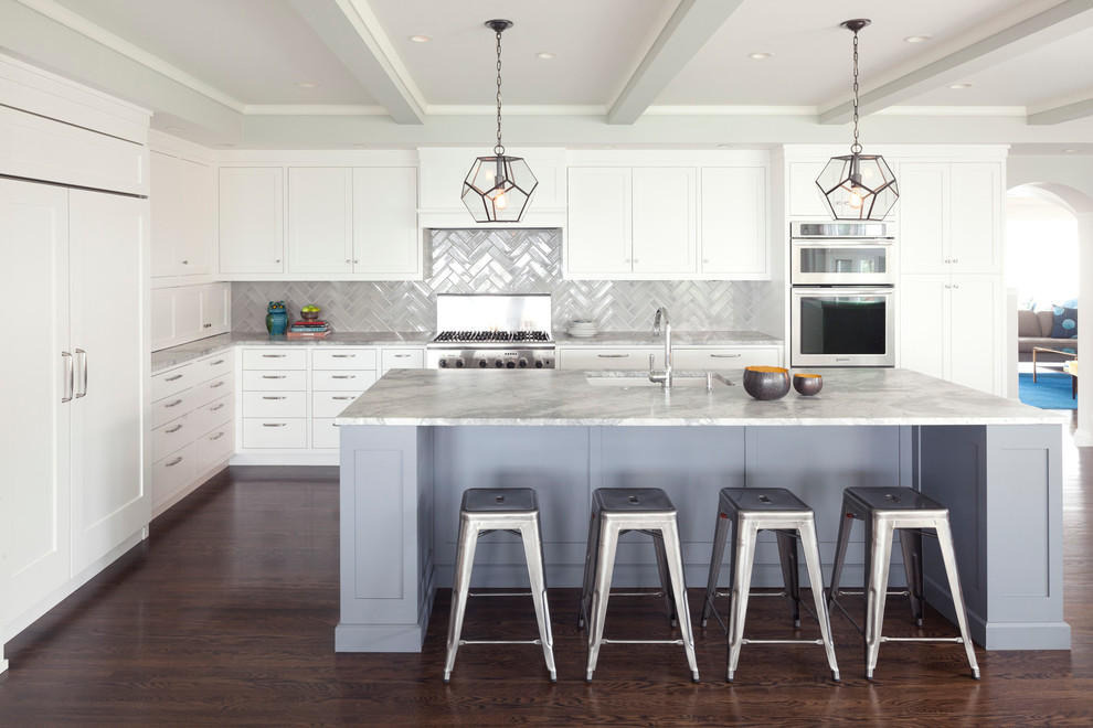 Design ideas for a mid-sized transitional l-shaped kitchen in Minneapolis with an undermount sink, shaker cabinets, white cabinets, marble benchtops, grey splashback, ceramic splashback, stainless steel appliances, dark hardwood floors and with island.