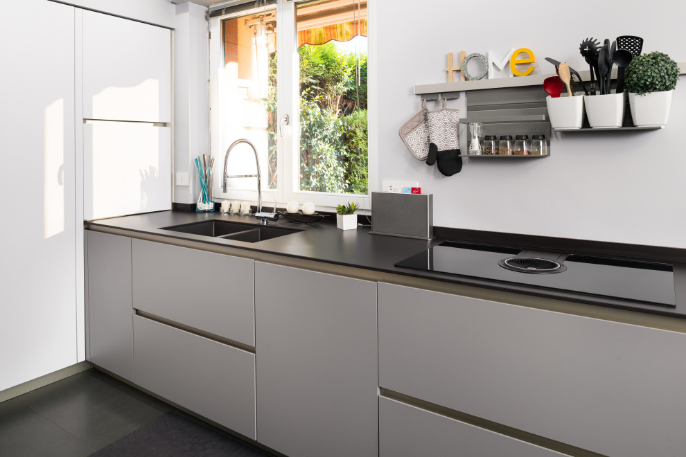 This is an example of a mid-sized modern kitchen in Turin with a double-bowl sink, grey cabinets, laminate benchtops, porcelain floors, grey floor and grey benchtop.