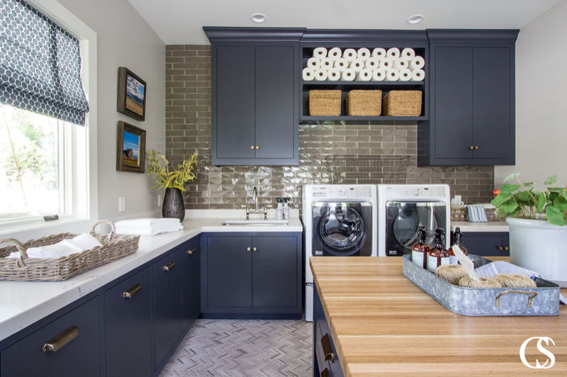 Traditional u-shaped laundry room in Salt Lake City with a drop-in sink, flat-panel cabinets, blue cabinets, brown splashback, brick splashback, grey walls and a side-by-side washer and dryer.