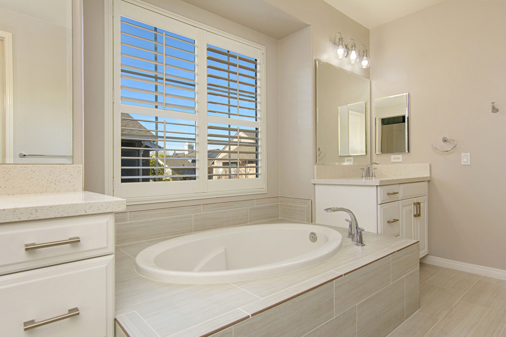 Photo of a large modern master bathroom in San Diego with recessed-panel cabinets, white cabinets, a drop-in tub, an alcove shower, a two-piece toilet, yellow tile, ceramic tile, white walls, porcelain floors, engineered quartz benchtops, a hinged shower door, an undermount sink, white floor, white benchtops, a double vanity and a built-in vanity.