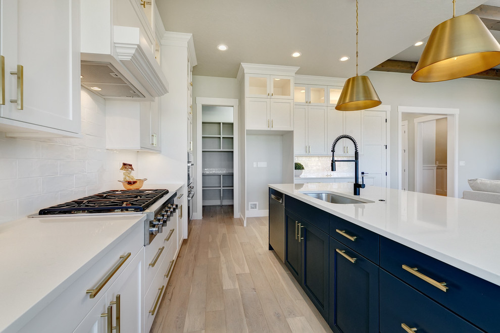 Design ideas for a large arts and crafts u-shaped eat-in kitchen in Boise with an undermount sink, recessed-panel cabinets, white cabinets, quartz benchtops, white splashback, brick splashback, stainless steel appliances, light hardwood floors, with island, beige floor and white benchtop.