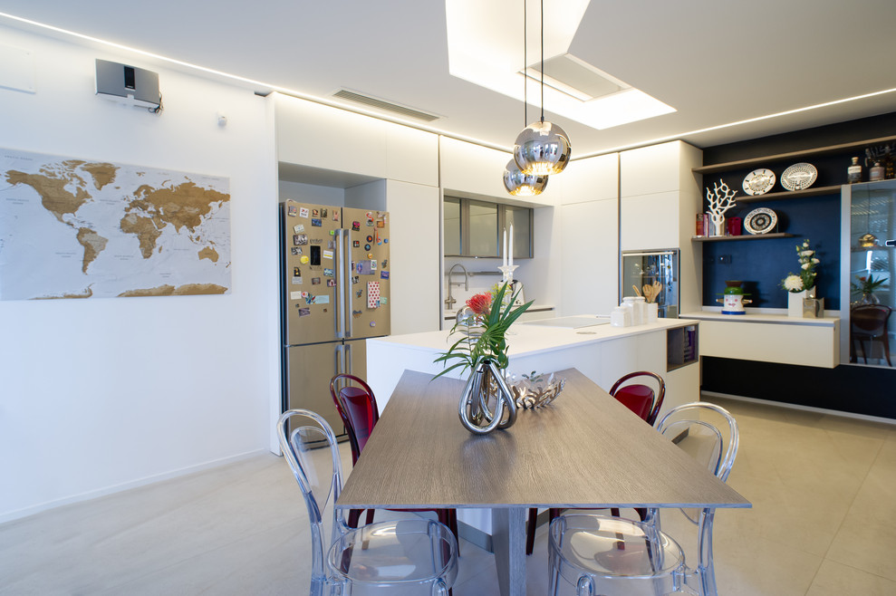 Inspiration for a large modern u-shaped eat-in kitchen in Rome with an integrated sink, glass-front cabinets, white cabinets, solid surface benchtops, black appliances, porcelain floors, with island, white floor and white benchtop.