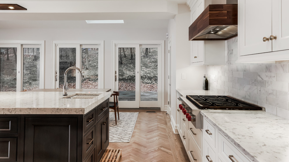 Photo of a large transitional eat-in kitchen in New York with an undermount sink, quartz benchtops, white splashback, marble splashback, stainless steel appliances, with island, brown floor and white benchtop.