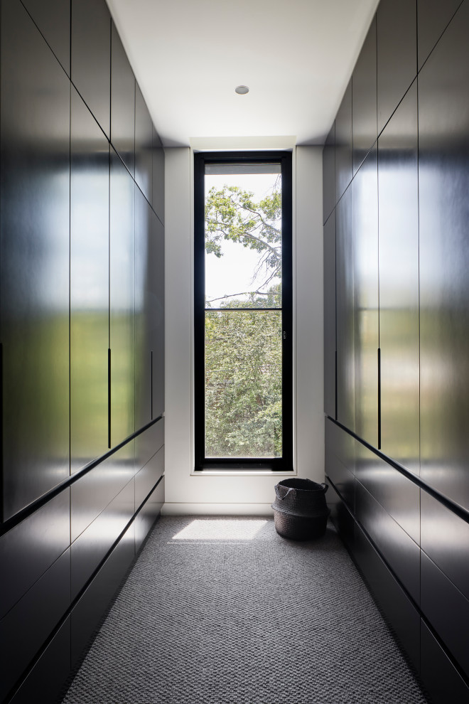 Design ideas for a mid-sized contemporary gender-neutral walk-in wardrobe in Melbourne with flat-panel cabinets, black cabinets, carpet and grey floor.