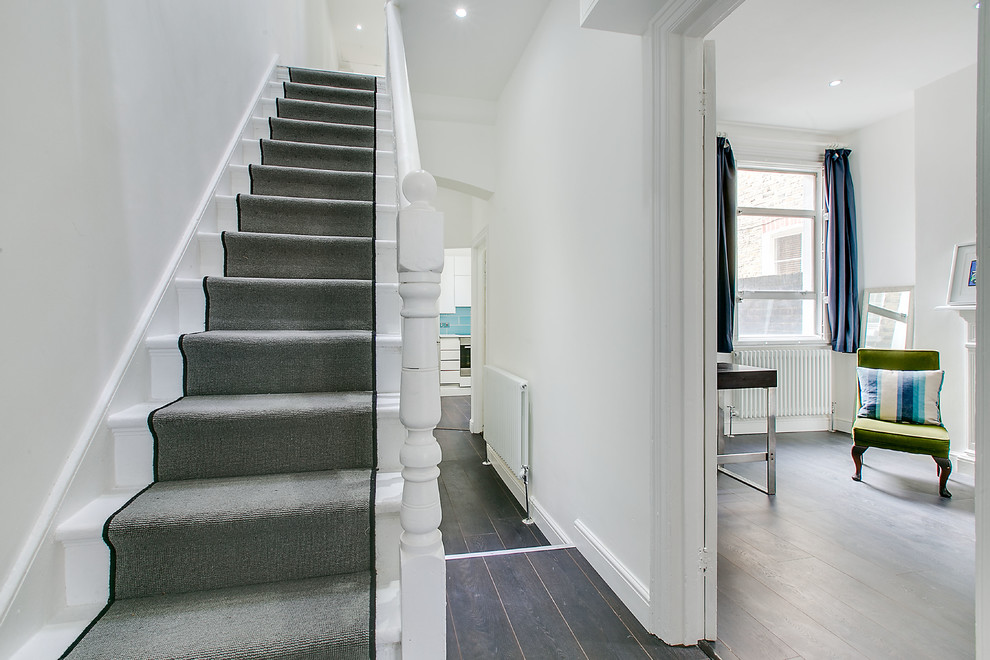 Mid-sized transitional carpeted straight staircase in London with carpet risers.