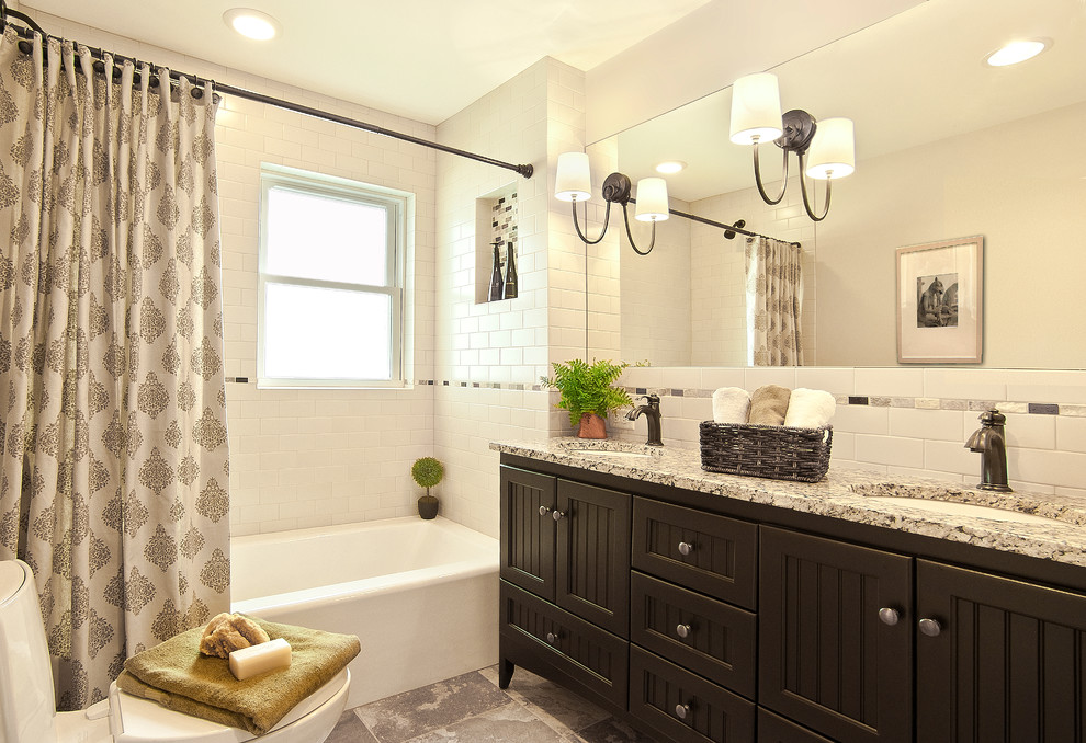 This is an example of a traditional bathroom in Milwaukee with an undermount sink, dark wood cabinets, an alcove tub, a shower/bathtub combo, white tile, subway tile and white walls.