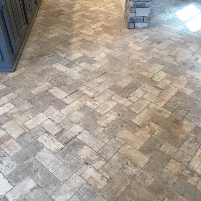 Inspiration for a mid-sized transitional galley brick floor and gray floor enclosed kitchen remodel with an undermount sink, raised-panel cabinets, white cabinets, wood countertops, gray backsplash, matchstick tile backsplash, stainless steel appliances and an island