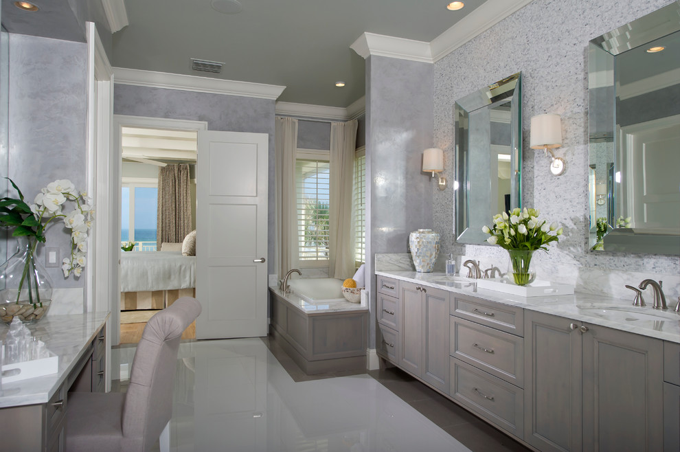 Photo of an expansive beach style master bathroom in Orlando with an undermount sink, recessed-panel cabinets, grey cabinets, a drop-in tub, gray tile, white tile, mosaic tile, grey walls, porcelain floors, marble benchtops and white floor.