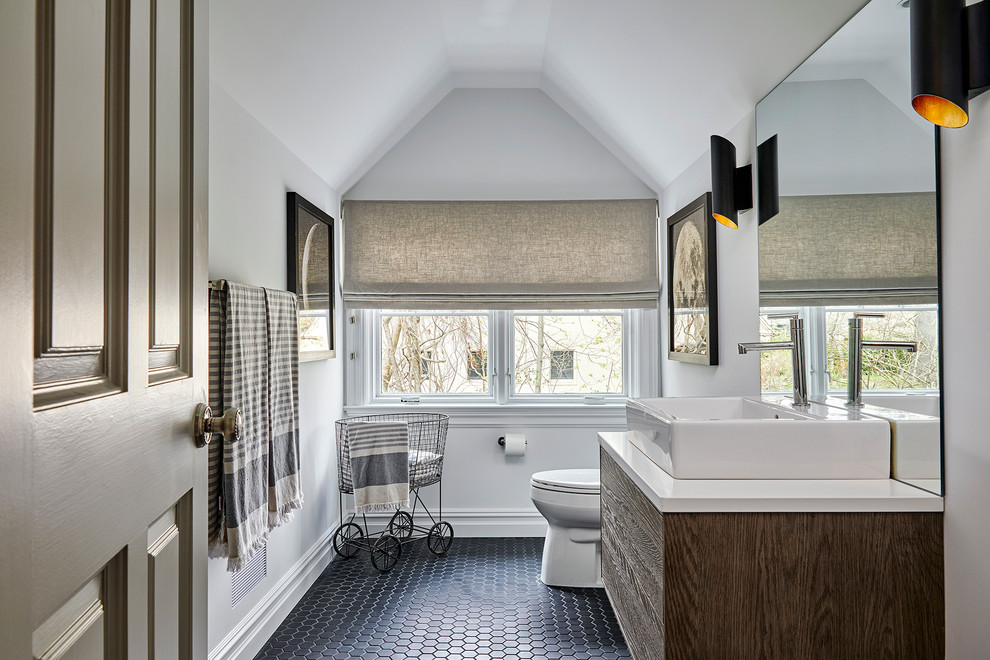 Inspiration for a mid-sized transitional bathroom in New York with flat-panel cabinets, dark wood cabinets, white walls, mosaic tile floors, a vessel sink, solid surface benchtops, black floor and a two-piece toilet.