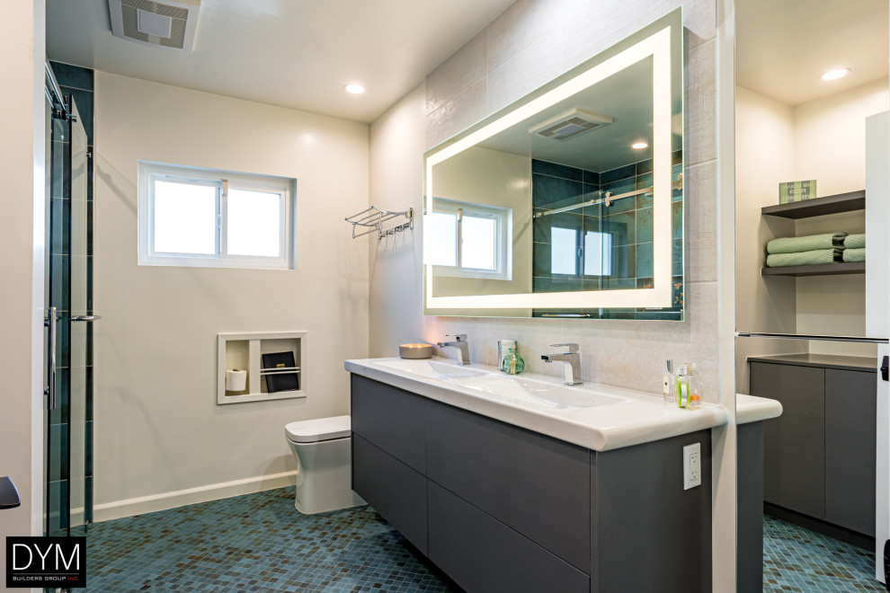 Photo of a large contemporary master bathroom in Los Angeles with flat-panel cabinets, grey cabinets, a one-piece toilet, white tile, marble, white walls, mosaic tile floors, a drop-in sink, solid surface benchtops, blue floor, white benchtops, a laundry, a double vanity, a built-in vanity, wallpaper, wallpaper, an alcove shower and a hinged shower door.