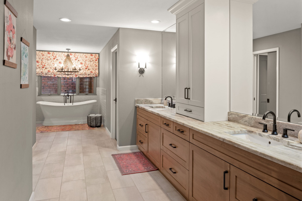 Photo of a large eclectic ensuite bathroom in Tampa with shaker cabinets, light wood cabinets, a freestanding bath, a one-piece toilet, grey tiles, porcelain tiles, grey walls, plywood flooring, a submerged sink, granite worktops, grey floors, an open shower, multi-coloured worktops, a shower bench, double sinks, a built in vanity unit and a built-in shower.