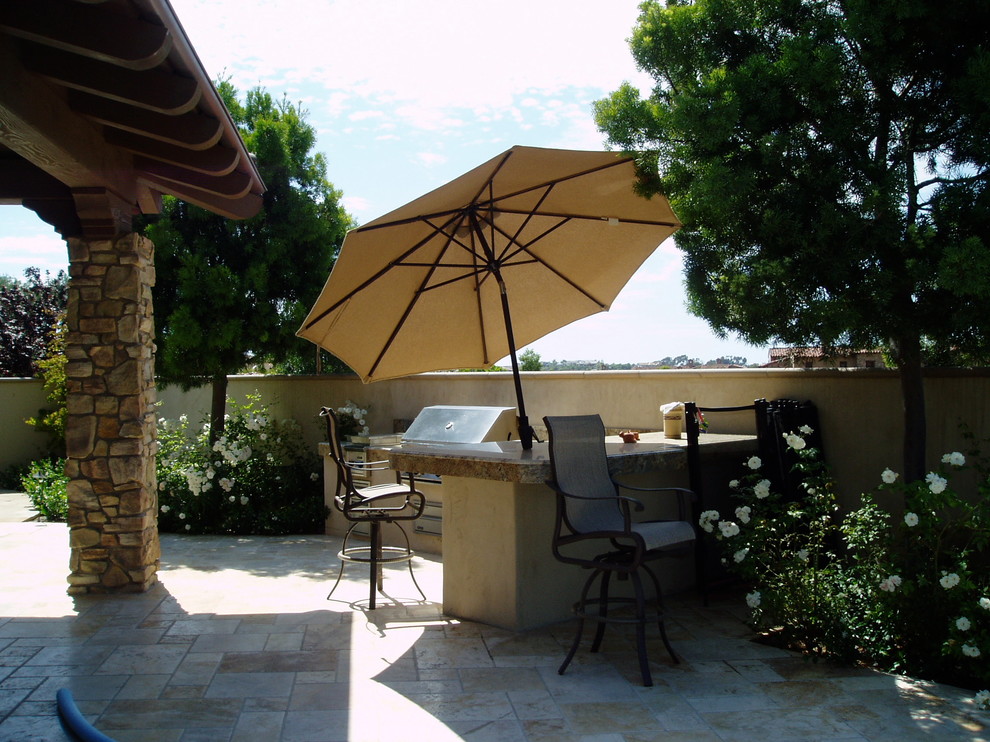Photo of a mediterranean backyard patio in San Diego with an outdoor kitchen, tile and a roof extension.