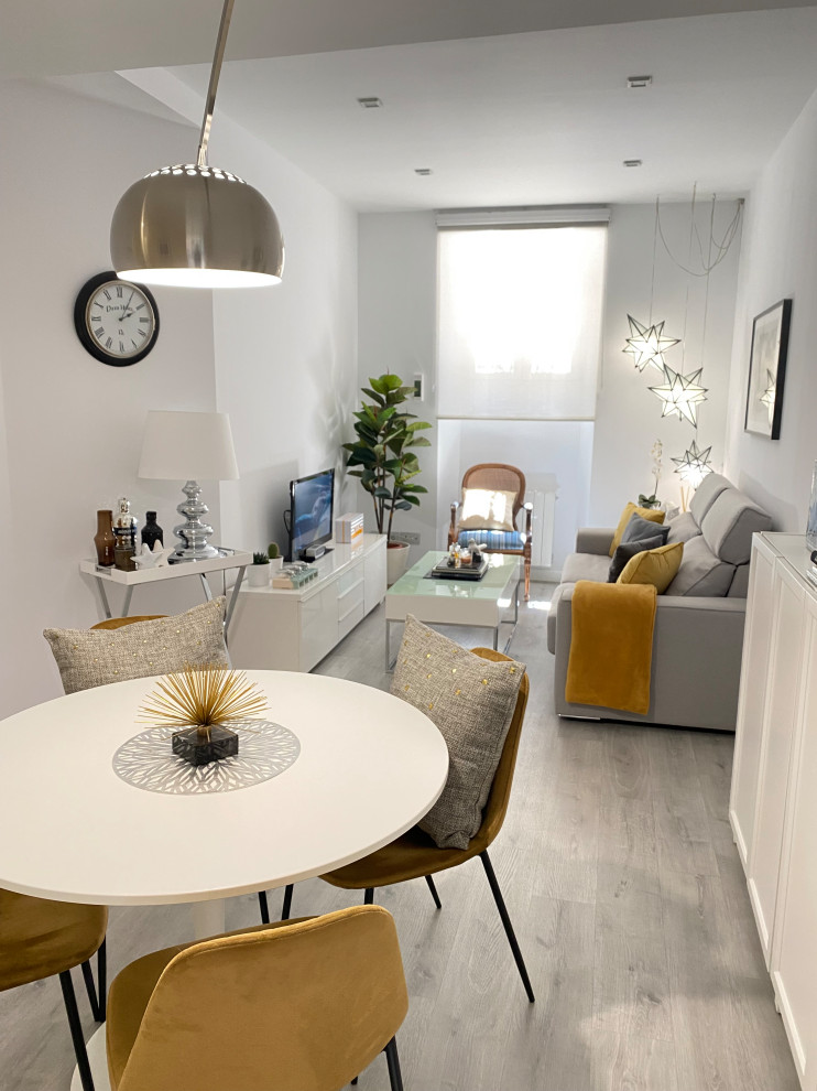 Modelo de salón abierto y gris y blanco moderno pequeño sin chimenea con paredes blancas, suelo de madera clara, televisor independiente, suelo gris y cortinas