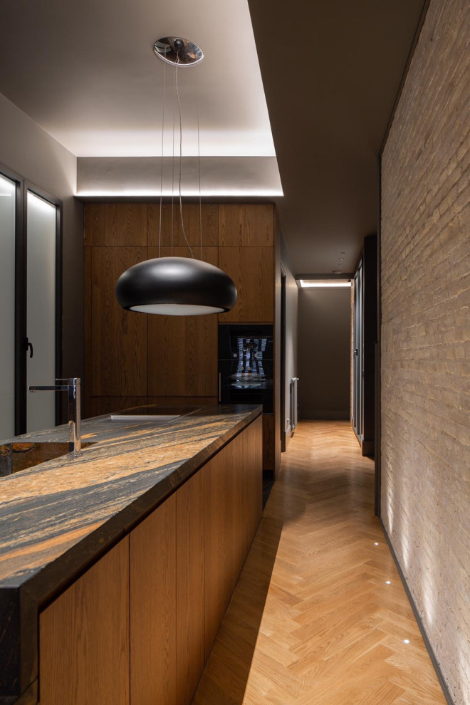 This is an example of a large contemporary single-wall enclosed kitchen in Valencia with an integrated sink, flat-panel cabinets, medium wood cabinets, marble worktops, integrated appliances, marble flooring, an island, brown floors, brown worktops and exposed beams.