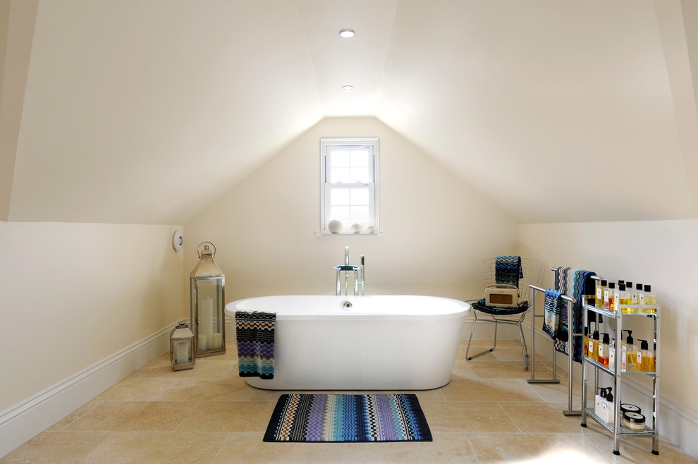 This is an example of an expansive contemporary bathroom in Essex with a freestanding tub, beige tile, stone tile and beige walls.