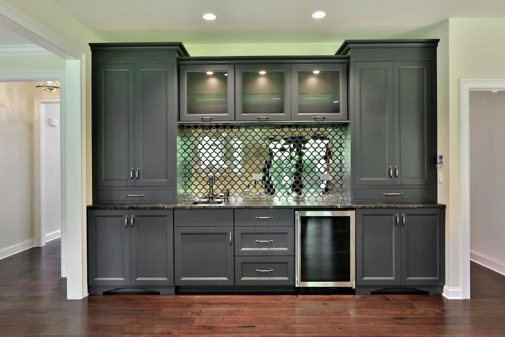 Wet bar - transitional dark wood floor wet bar idea in New York with an undermount sink, furniture-like cabinets, gray cabinets, granite countertops and mirror backsplash