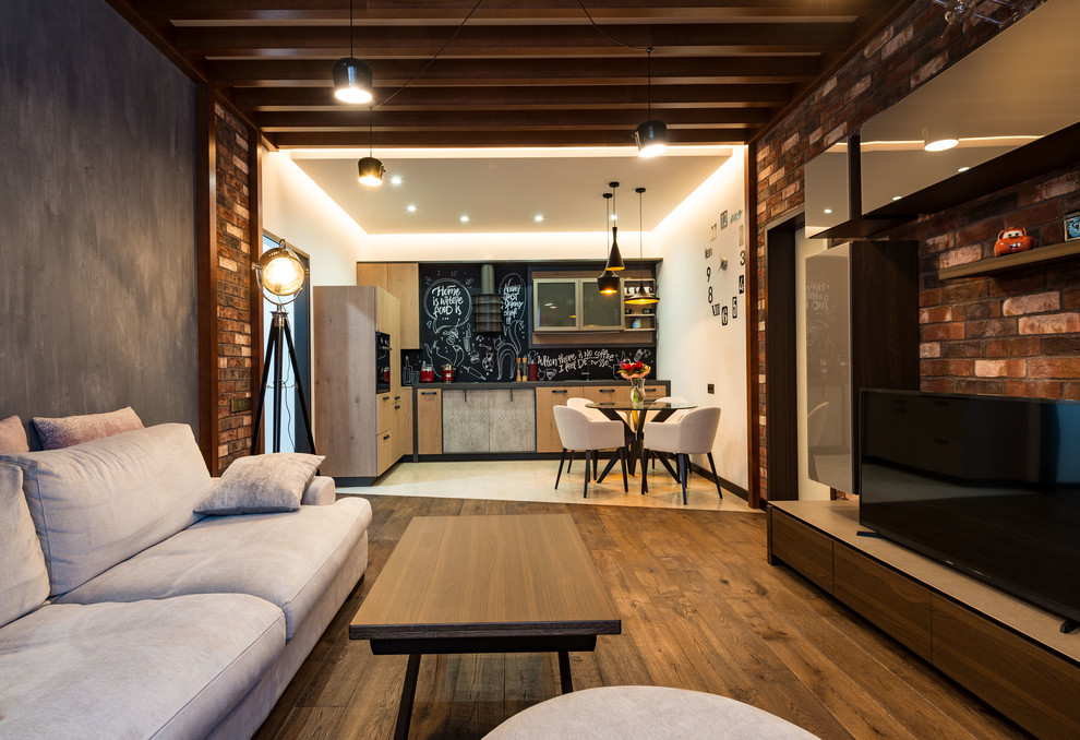 This is an example of a mid-sized industrial loft-style living room in Moscow with multi-coloured walls, medium hardwood floors, a freestanding tv and brown floor.