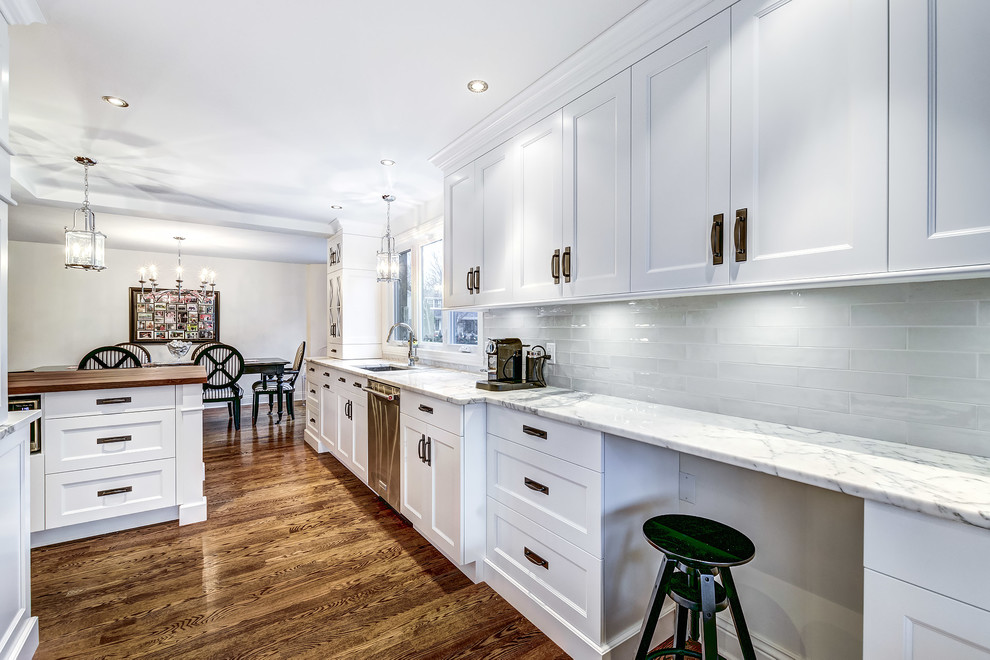 Inspiration for a large transitional kitchen in Montreal with an undermount sink, shaker cabinets, white cabinets, wood benchtops, white splashback, ceramic splashback, stainless steel appliances, medium hardwood floors and brown floor.