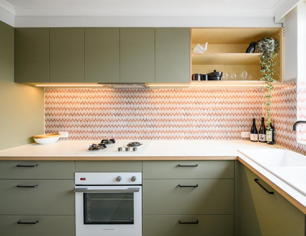 This is an example of a small scandinavian l-shaped separate kitchen in Melbourne with a double-bowl sink, flat-panel cabinets, green cabinets, laminate benchtops, multi-coloured splashback, ceramic splashback, white appliances, ceramic floors, beige floor and white benchtop.