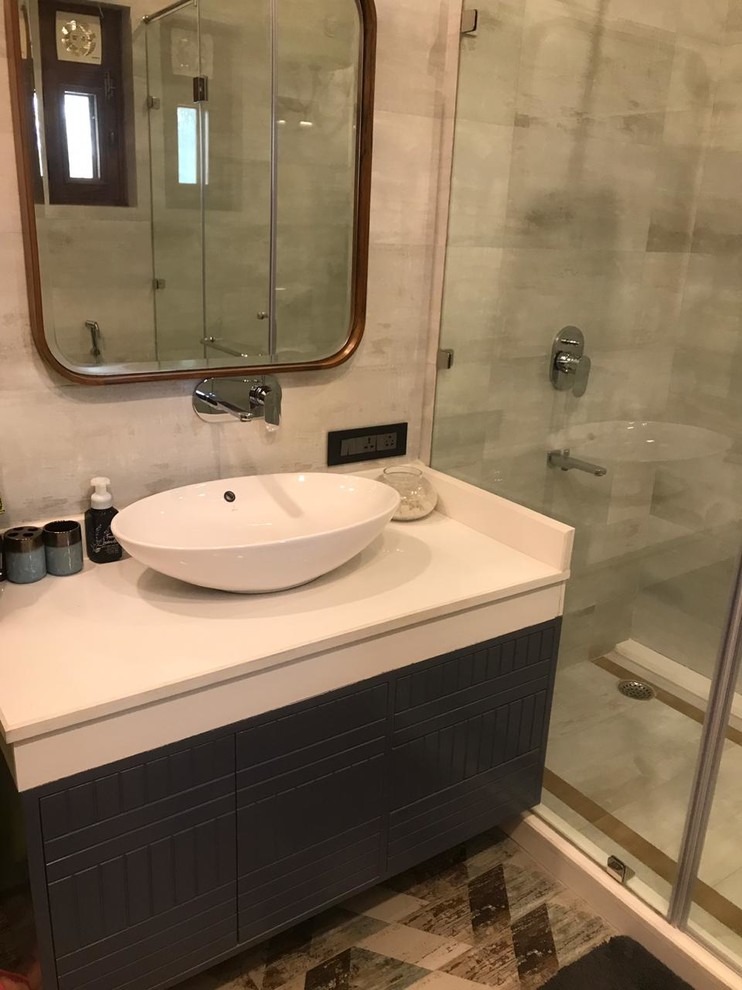 Photo of a mid-sized transitional master bathroom in Sydney with furniture-like cabinets, blue cabinets, a freestanding tub, a shower/bathtub combo, a wall-mount toilet, gray tile, ceramic tile, grey walls, ceramic floors, a console sink, marble benchtops, brown floor, a hinged shower door and white benchtops.