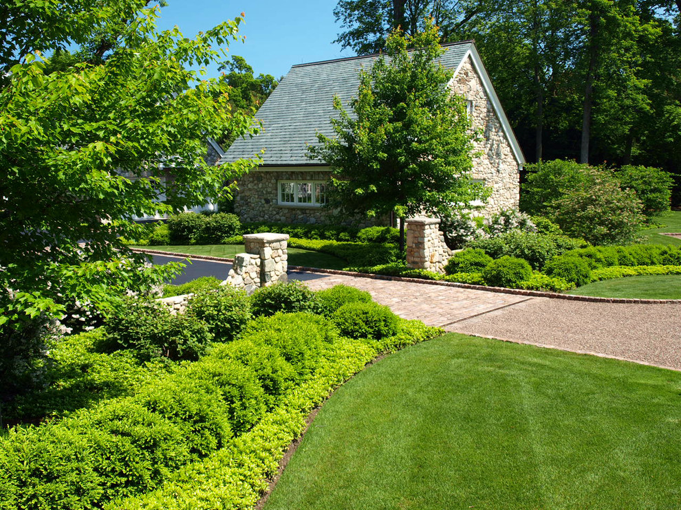 This is an example of an expansive traditional front yard partial sun driveway for summer in Chicago with gravel.