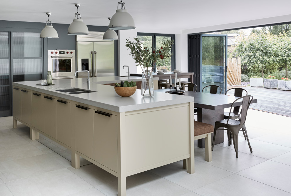 This is an example of a contemporary u-shaped kitchen/diner in London with a double-bowl sink, flat-panel cabinets, beige cabinets, engineered stone countertops, stainless steel appliances, an island, grey floors and grey worktops.