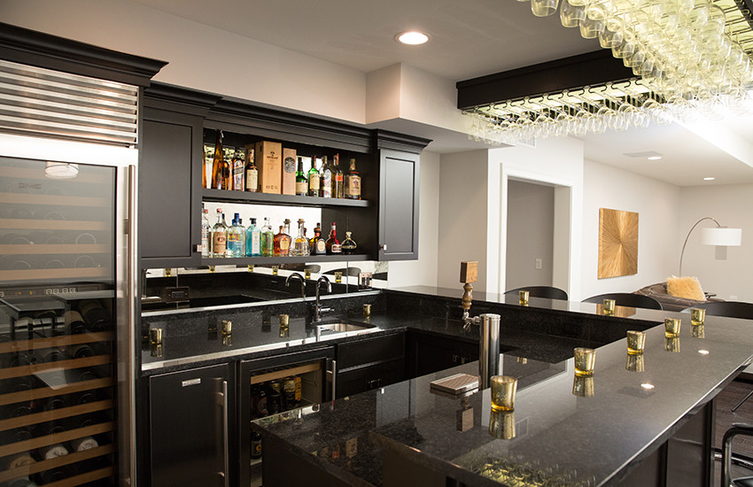 Design ideas for a mid-sized modern u-shaped seated home bar in Chicago with an undermount sink, shaker cabinets, black cabinets, granite benchtops, multi-coloured splashback, mirror splashback and dark hardwood floors.