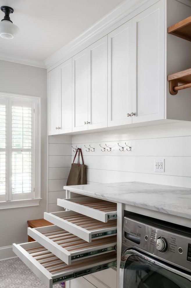 This is an example of a mid-sized traditional single-wall utility room in Atlanta with a single-bowl sink, shaker cabinets, white cabinets, marble benchtops, grey walls, ceramic floors, a side-by-side washer and dryer, grey floor and white benchtop.
