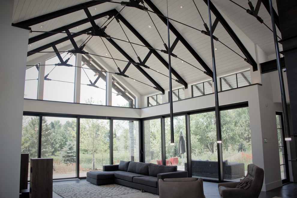 Photo of an expansive modern enclosed family room in Denver with white walls, concrete floors, a hanging fireplace, a concrete fireplace surround and black floor.
