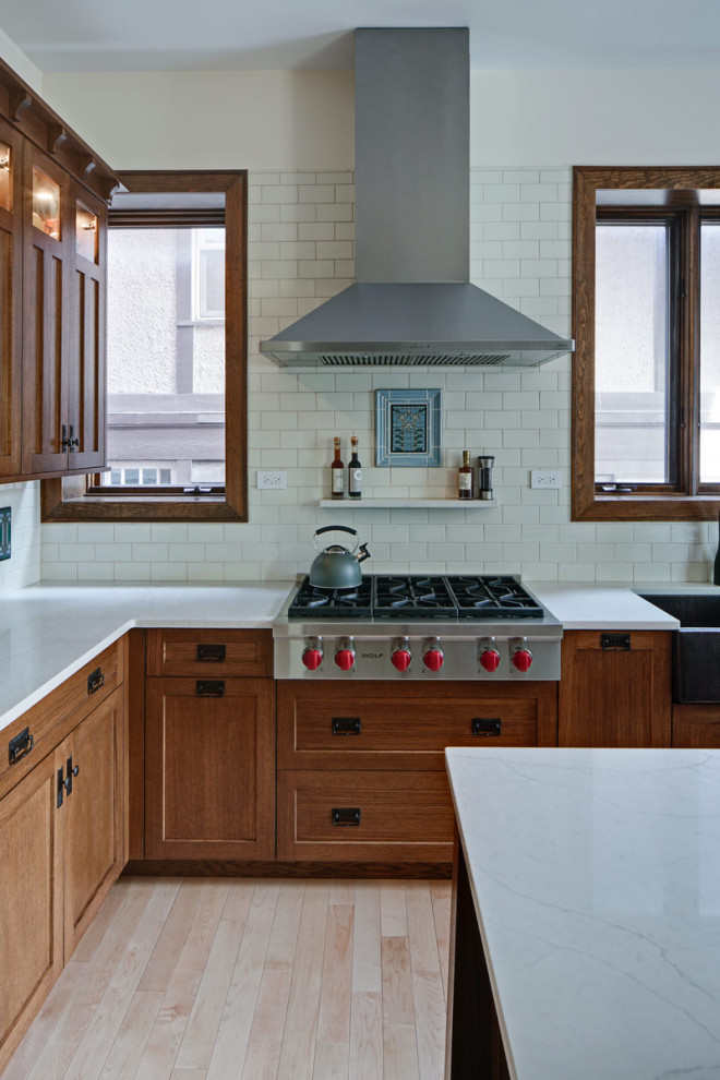 Idéer för stora amerikanska vitt kök, med en rustik diskho, luckor med infälld panel, skåp i mellenmörkt trä, bänkskiva i kvarts, vitt stänkskydd, stänkskydd i keramik, integrerade vitvaror, ljust trägolv, en köksö och beiget golv