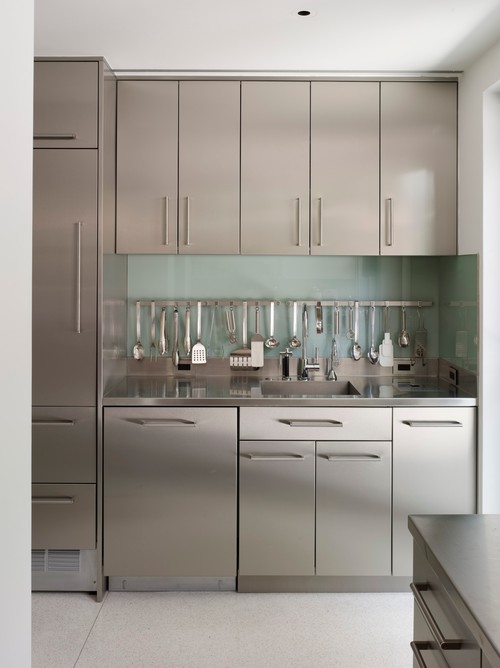 Compact kitchen wall with sleek stainless steel cabinets, integrated fridge and organized utensil rail