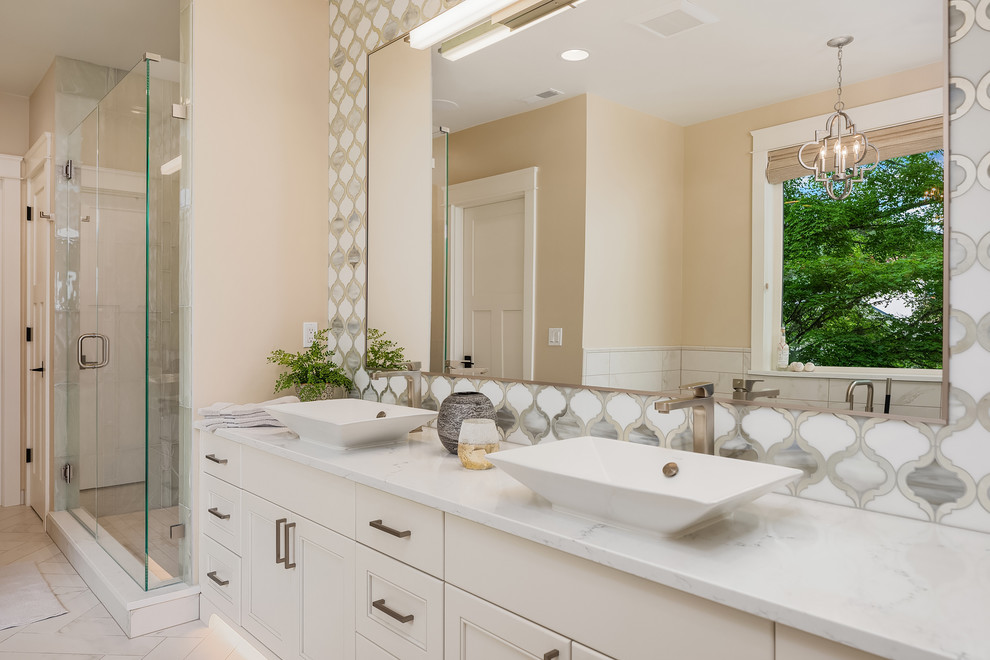 Mid-sized transitional master wet room bathroom in Seattle with recessed-panel cabinets, white cabinets, a drop-in sink, marble benchtops, a hinged shower door, white benchtops, a drop-in tub, multi-coloured tile, ceramic tile, beige walls and ceramic floors.