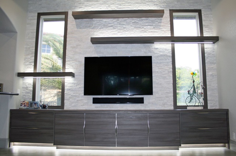 This is an example of a mid-sized contemporary open concept family room in Miami with grey walls, porcelain floors, a wall-mounted tv and grey floor.