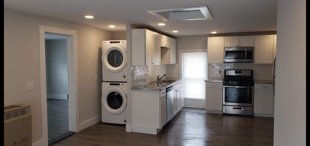 Exempel på ett litet modernt grå grått kök, med en nedsänkt diskho, skåp i shakerstil, vita skåp, bänkskiva i rostfritt stål, vitt stänkskydd, stänkskydd i tunnelbanekakel, rostfria vitvaror, vinylgolv och brunt golv