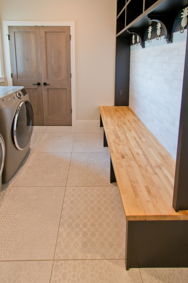 Photo of a transitional galley utility room in Other with white splashback, beige walls, vinyl floors, a side-by-side washer and dryer and beige floor.